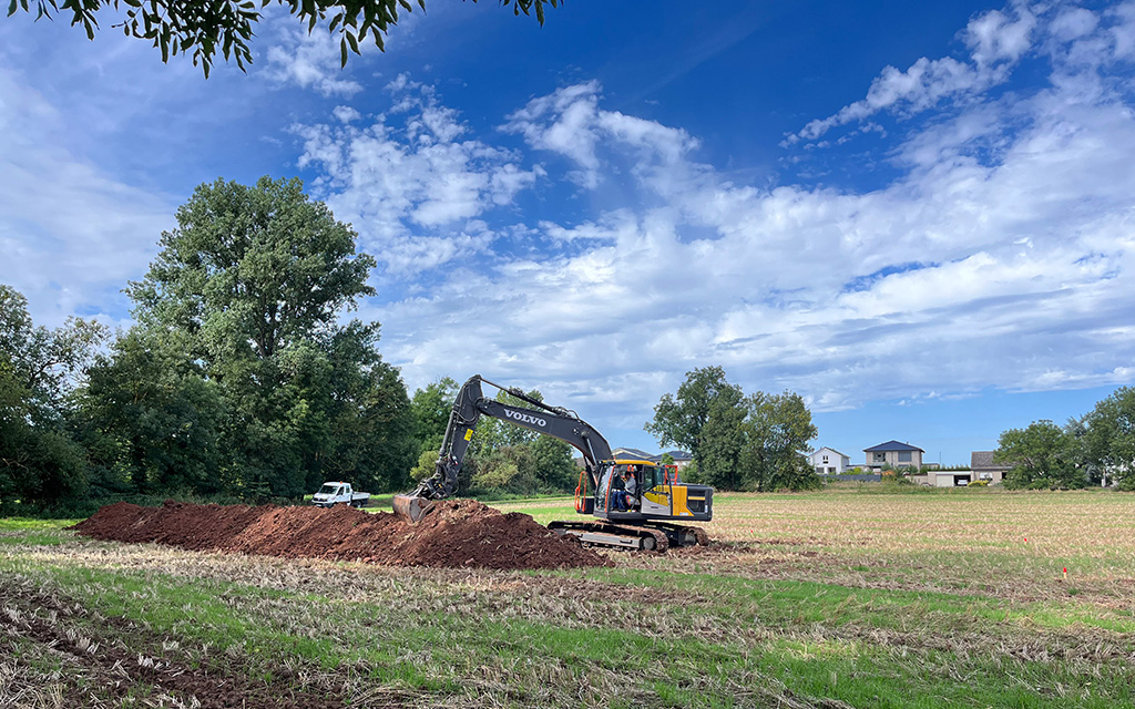 Bagger arbeitet auf einem Feld bei der Renaturierung vom Rotbach