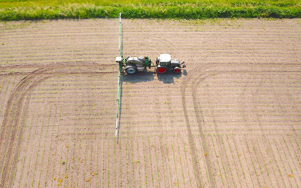 Ein Traktor düngt ein Feld