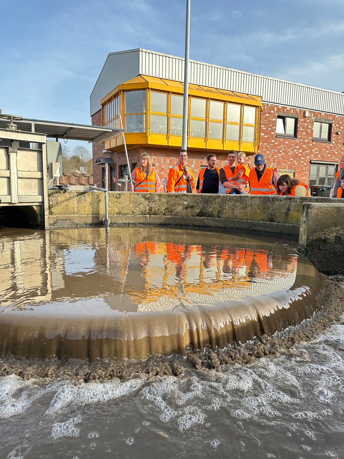 2025_weltwassertag_ka-weilerswist_ser_ (1) Chemische Reinigung der Kläranlage Weilerswist mit schäumendem Abwasser und Besuchergruppe in Warnwesten