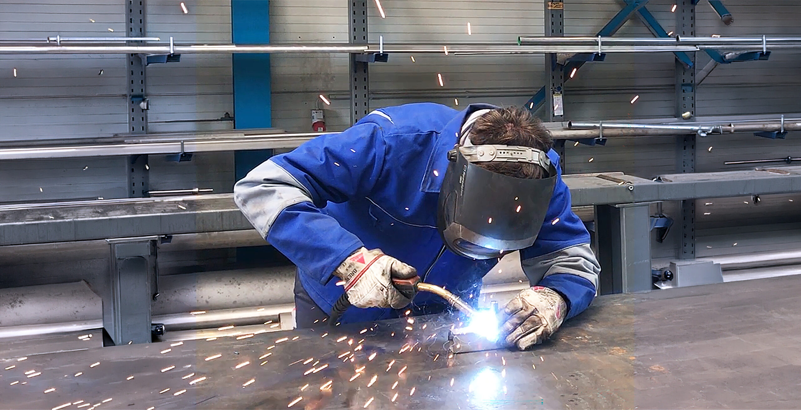 Industriemechaniker*in (Instandhaltung) Industriemechaniker*in (Instandhaltung), Mann schweißt Teile aneinander, Funken fliegen